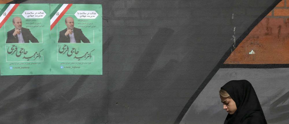 Im Iran geht eine Frau an einem Wahlkampfplakat vorbei. 