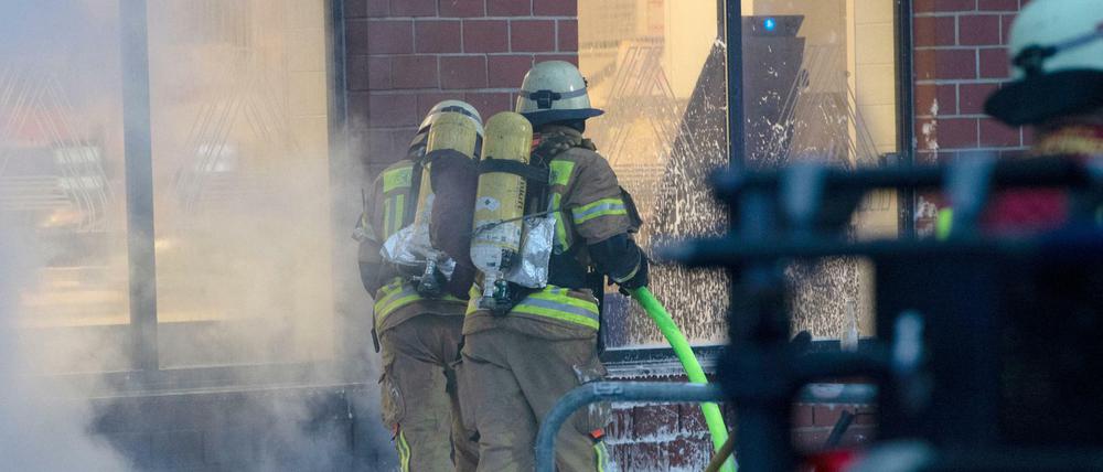 Einsatzkräfte der Feuerwehr löschen den Brand im Keller von einem Wohnhaus in der Hermannstraße in Berlin-Neukölln. Bei dem Brand sind am Samstagnachmittag mehrere Menschen verletzt worden. 