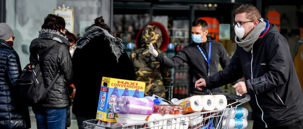 Menschen im italienischen Casalpusterlengo horten Lebensmittel. Vor dem Supermarkt müssen sie Schlange stehen.
