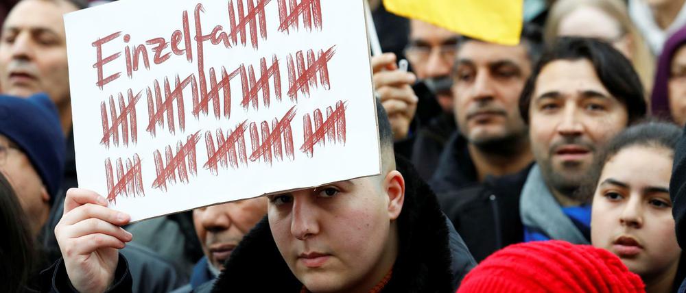 Ein Demonstrant hält in Hanau am Sonntag, 23.2., ein Plakat hoch.