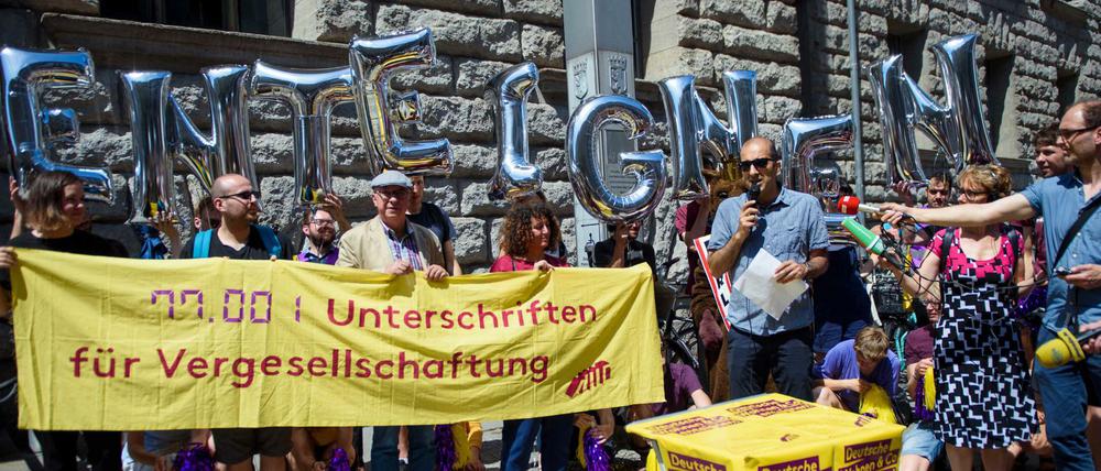 Rouzbeh Taheri, Sprecher der Initiative Deutsche Wohnen &amp; Co enteignen, steht vor einem Transparent.