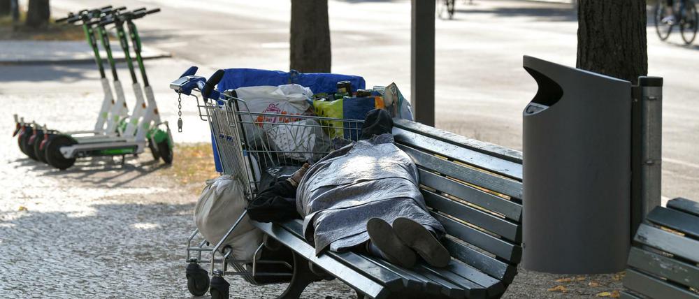 Ein Obdachloser schläft auf einer Bank auf dem Boulevard Unter den Linden.