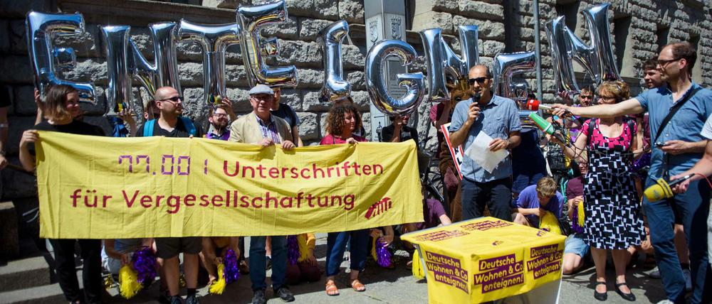Rouzbeh Taheri, Sprecher der Initiative Deutsche Wohnen &amp; Co enteignen, steht vor einem Transparent "77.001 Unterschriften für Vergesellschaftung" und spricht zu anderen Mitgliedern und freiwilligen Helfern der Initiative vor der Übergabe der Unterschriften für ein Volksbegehren an die Senatsverwaltung für Inneres und Sport.