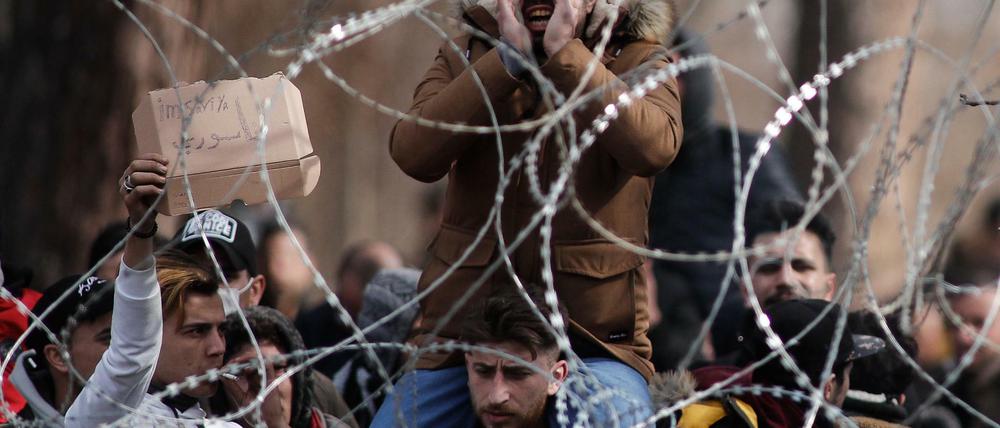 Migranten und Flüchtlinge hinter einem Drahtzaun an der Grenze zwischen Griechenland und der Türkei in der Nähe des geschlossenen Grenzübergangs Kastanies. 