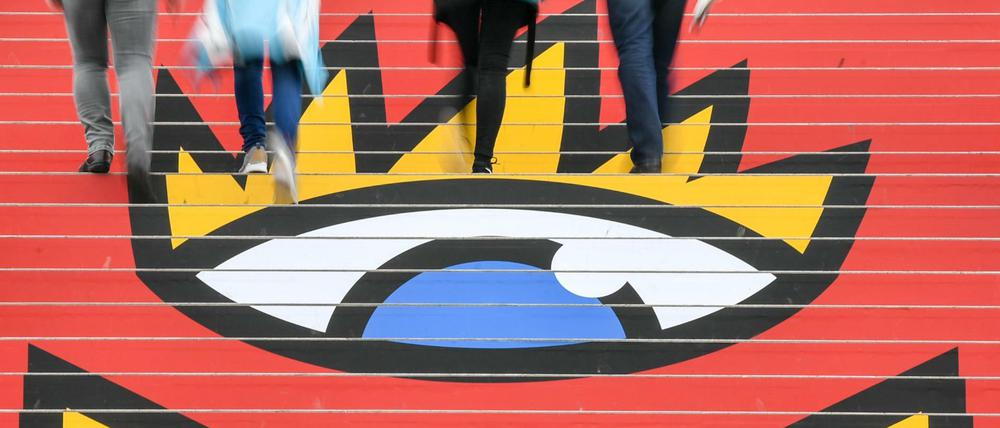 Sachsen, Leipzig: Besucher gehen in der Glashalle über die Treppe mit dem Logo der Leipziger Buchmesse.