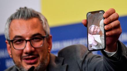 Der iranische Produzent Farzad Pak hält während der 70. Berlinale ein Handy mit dem zugeschalteten Regisseur Mohammad Rasoulof hoch. Rasoulof durfte nicht anreisen.