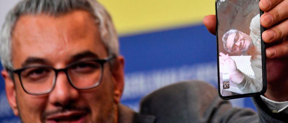 Der iranische Produzent Farzad Pak hält während der 70. Berlinale ein Handy mit dem zugeschalteten Regisseur Mohammad Rasoulof hoch. Rasoulof durfte nicht anreisen.
