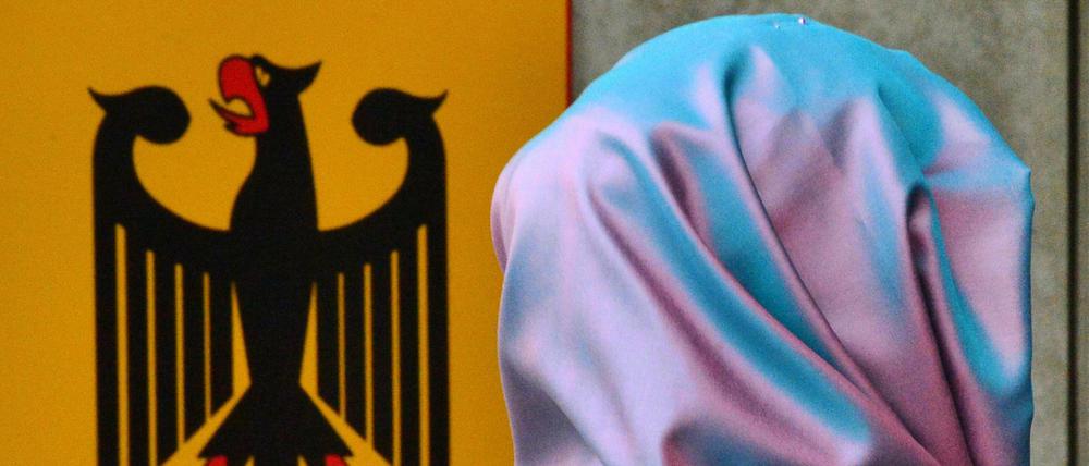 Kopftuch und Bundesadler an einer Behörde: Schwieriges Verhältnis.