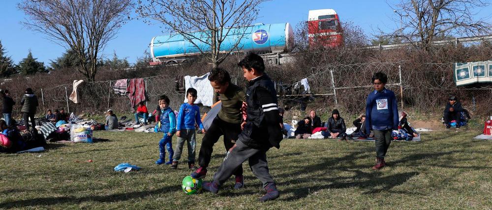 Flüchtlingskinder spielen auf türkischer Seite vor dem Grenzzaun zu Griechenland Fußball.