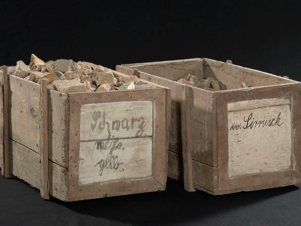 Historische Transportkisten, die mit Ziegelfragmenten gefüllt siind.