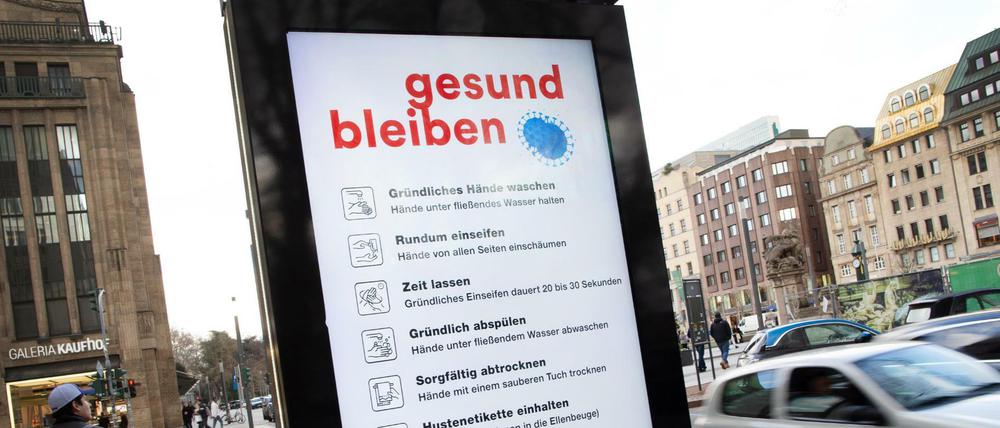 Auf einer Tafel werden in der Innenstadt von Düsseldorf Verhaltensregeln zum Coronavirus angezeigt.