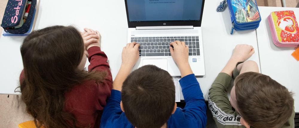 Schüler einer 3. Klasse sitzen in einem Klassenzimmer der Grundschule Georgius Agricola vor einem Laptop.