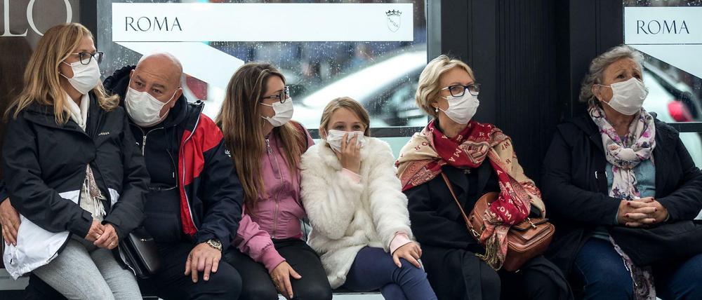 Italien: Reisende mit Mundschutzmasken warten an einer Bushaltestelle. Italien hat die höchste Zahl an nachgewiesenen Covid-19-Toten nach China.