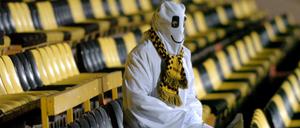 Ein als Geist verkleideter Mann sitzt auf den leeren Rängen eines Fußballstadions