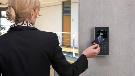 Im Kasten. Eine Frau demonstriert mit einer Chipkarte ein modernes Verfahren zur Arbeitszeiterfassung.