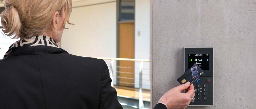 Im Kasten. Eine Frau demonstriert mit einer Chipkarte ein modernes Verfahren zur Arbeitszeiterfassung.