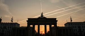 Im Licht der aufgehenden Sonne ist das Brandenburger Tor nur als Silhouette zu erkennen.