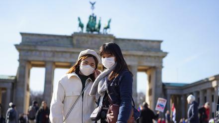 Touristen aus Hongkong stehen mit Mundschutz vor dem Brandenburger Tor.