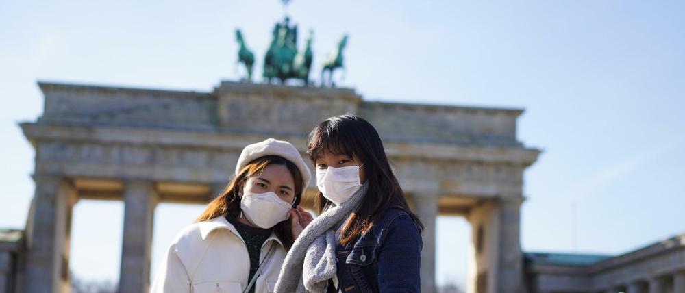 Touristen aus Hongkong stehen mit Mundschutz vor dem Brandenburger Tor.