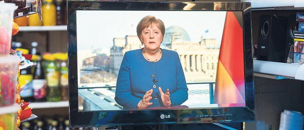 In einem Berliner Spätkauf läuft die TV-Ansprache von Angela Merkel auf einem kleinen Fernseher.