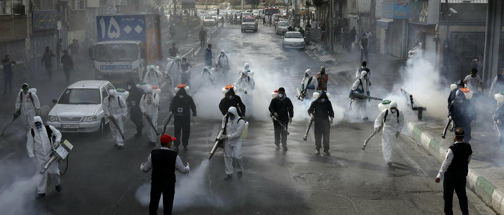 Feuerwehrleute desinfizieren eine Straße in Teheran.