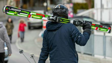 Ein Skifahrer geht mit geschulterten Skiern auf einer Straße. Tirol hat die Skisaison vorzeitig beendet. Die Region Paznauntal mit dem Touristenort Ischgl steht in Österreich neben weiteren Orten wegen einer erhöhten Zahl von Coronavirus-Fällen unter Quarantäne. 