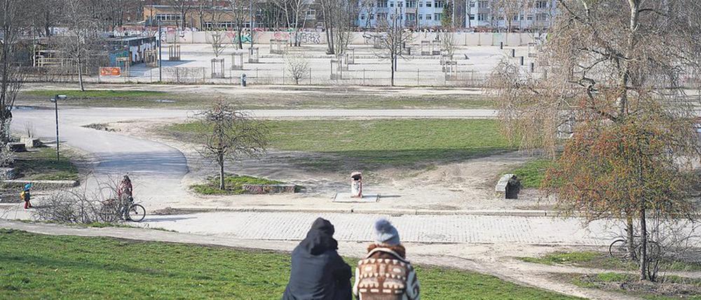 Ein junges Paar sitzt am Sonntag im leeren Mauerpark. Hier grillen, feiern, singen sonst Tausende.
