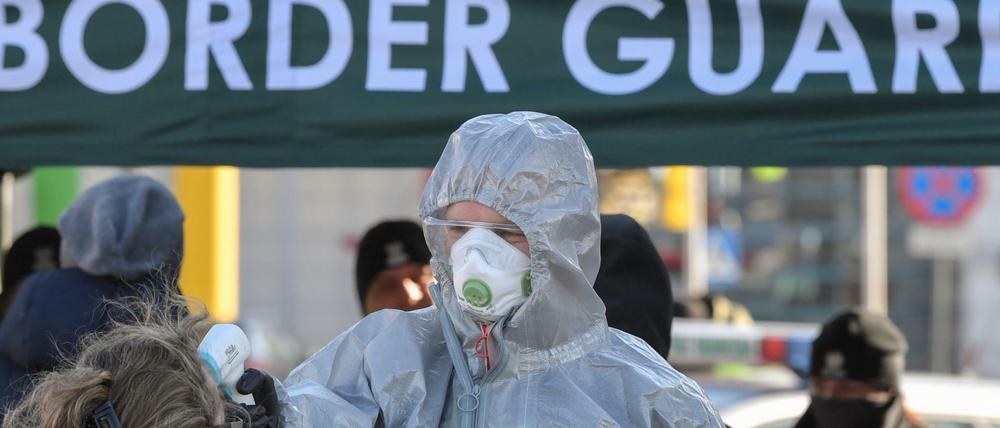 Polnische Sicherheitskräfte in Schutzkleidung messen an einem Grenzübergang die Körpertemperatur von Personen, die einreisen wollen. 
