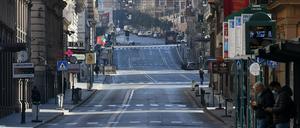 Menschen mit Mundschutzen stehen an einer Bushaltestelle in Rom. Der italienische Ministerpräsident Conte rechnet im Kampf gegen die Folgen der Coronavirus-Welle damit, dass die strikten Maßnahmen zur Eindämmung des Virus wie Laden- und Schulschließungen sowie die Ausgangssperren für die Bürger über ihre bisherigen Fristen verlängert würden. 