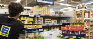 Ein Mitarbeiter von Edeka füllt ein Regal auf. 