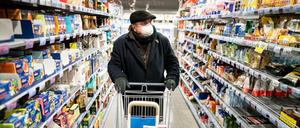 Ein Kunde kauft mit Mundschutz und Handschuhen am frühen Morgen in einem Supermarkt im Berliner Stadtteil Friedenau ein.