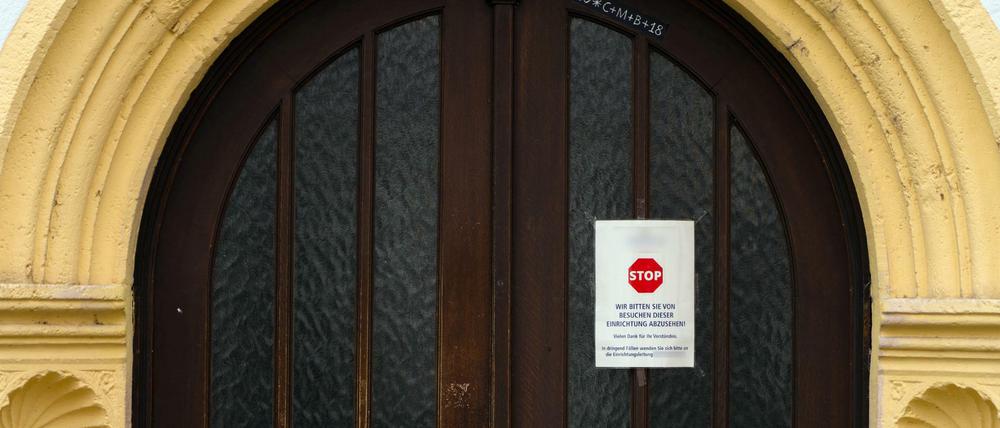 An einer Zugangstür zu einem Seniorenheim ist ein Schild angebracht, das von Besuchen dieser Einrichtung abrät.