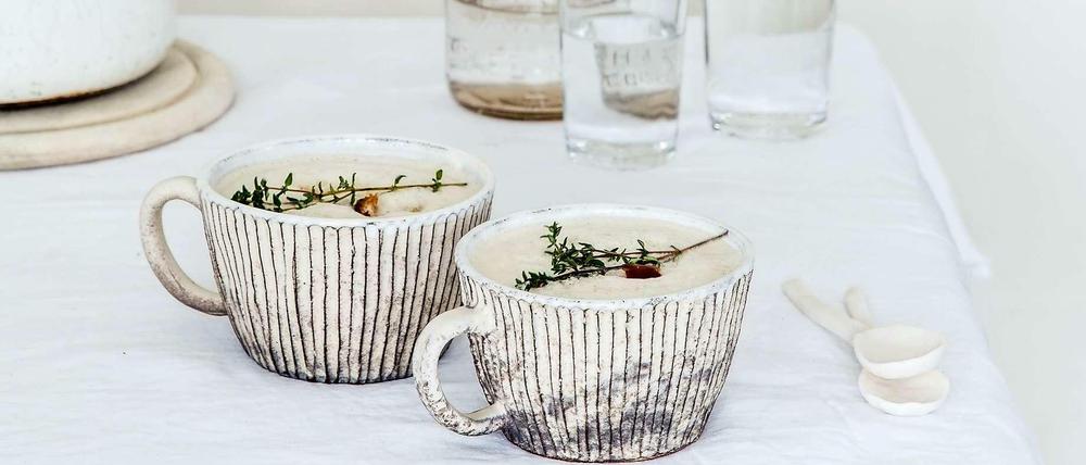 Ganz in Weiß. In rustikalen Keramiktassen serviert, mit frischen Kräutern und den Laugencroutons obenauf, ist die Selleriesuppe schon ein Augenschmaus. Und wie sie erst schmeckt!