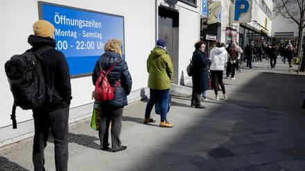 Menschen stehen in Berlin-Wilmersdorf vor einem Supermarkt Schlange.