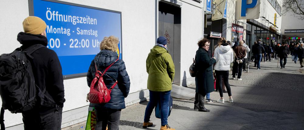 Menschen stehen in Berlin-Wilmersdorf vor einem Supermarkt Schlange.