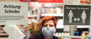 Ein Mitarbeiterin in einem Supermarkt in Dresden putzt vor Ladenöffnung eine Plexiglasscheibe, einen sogenannten "Spuckschutz", an der Kasse.