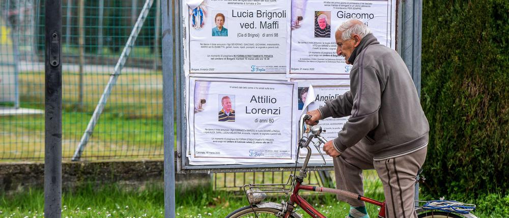 Ein Passant hält an den öffentlichen Todesanzeigen in einer Gemeinde der Lombardei.