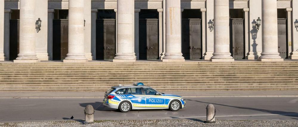 Ein Polizeiauto fährt an der leeren Treppe der bayerischen Staatsoper in München vorbei.