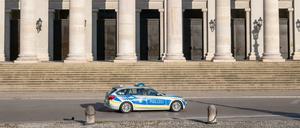 Ein Polizeiauto fährt an der leeren Treppe der bayerischen Staatsoper in München vorbei.