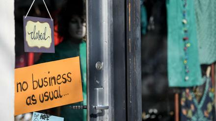 Ein der Eingangstür eines kleinen Ladengeschäfts hängen Schilder mit der Aufschrift «Closed», «no business as usual...»