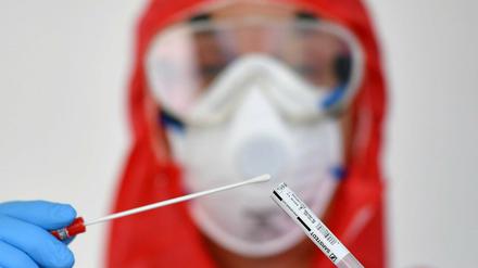 Ein Mitarbeiter eines Gesundheitsamtes mit einer Probe eines Corona-Tests. 