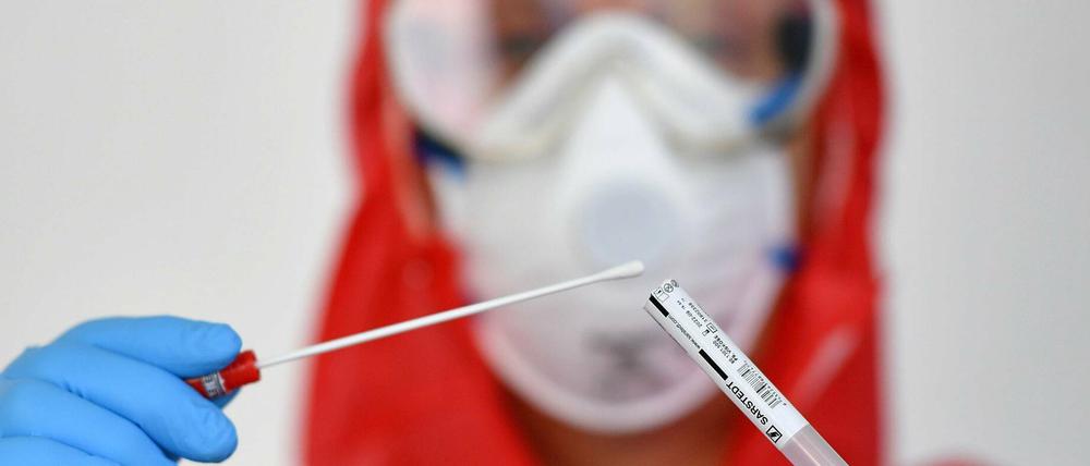 Ein Mitarbeiter eines Gesundheitsamtes mit einer Probe eines Corona-Tests. 