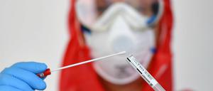 Ein Mitarbeiter eines Gesundheitsamtes mit einer Probe eines Corona-Tests. 