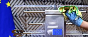 Ein Mann desinfiziert einen Tisch in Brüssel, bevor EU-Ratspräsident Charles Michel spricht. Das Coronavirus stellt die EU vor große Herausforderungen.