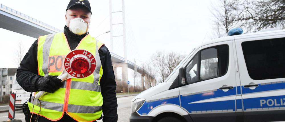 Fremde nicht erwünscht: Ein Polizeibeamter kontrolliert vor der Ziegelgrabenbrücke den Verkehr in Richtung der Insel Rügen.