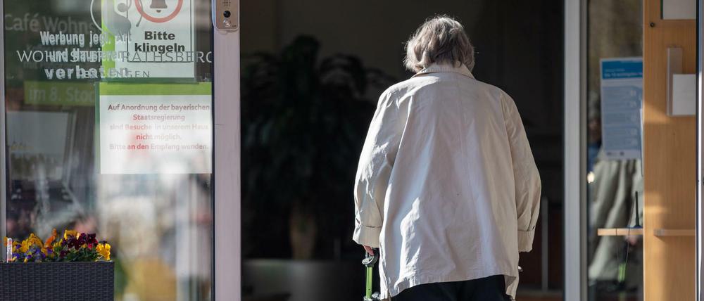 Eine Seniorin betritt mit ihrer Gehhilfe den Eingang eines Senioren-Wohnstifts. Wie weit soll die Isolierung gehen?