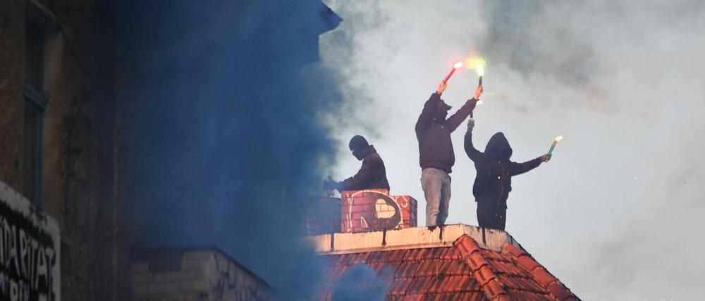 Unterstützer der linksradikalen «Revolutionären 1. Mai-Demonstration» in 2019 stehen mit Pyrotechnik in den Händen auf einem Dach in Friedrichshain.