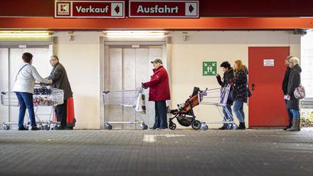 Menschen stehen mit Einkaufswagen vor einem Supermarkt und warten auf den Einlass, aufgenommen in Goerlitz Anfang April.