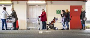 Menschen stehen mit Einkaufswagen vor einem Supermarkt und warten auf den Einlass, aufgenommen in Goerlitz Anfang April.
