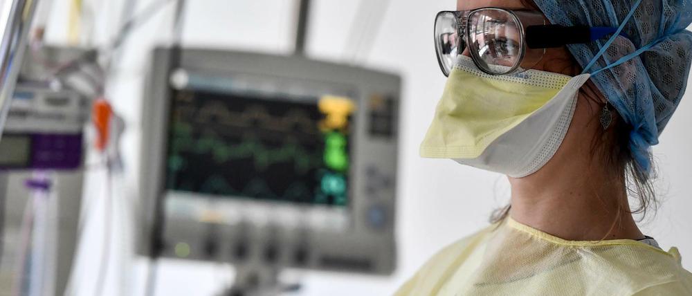 Eine Krankenpflegerin betreut einen Patienten auf der Intensivstation, der mit einem Beatmungsgerät versorgt wird.